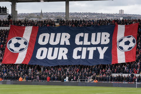 Giant football supporter banner across a stadium terrace — illustrative mock-up